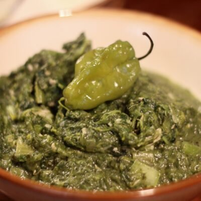 A bowl of callaloo with a whole pepper
