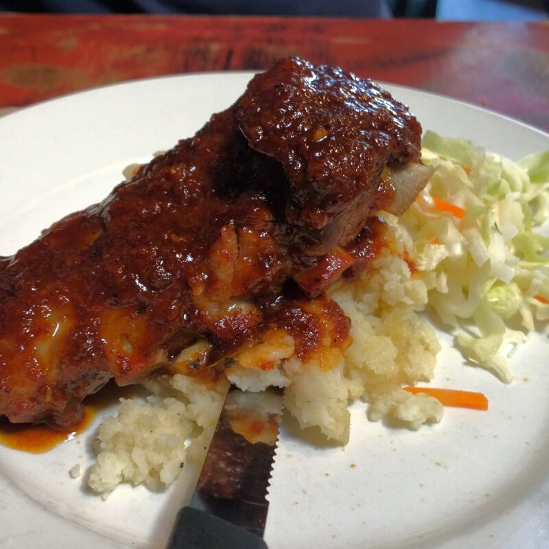 Jerk chicken with rice and salad on a white plate